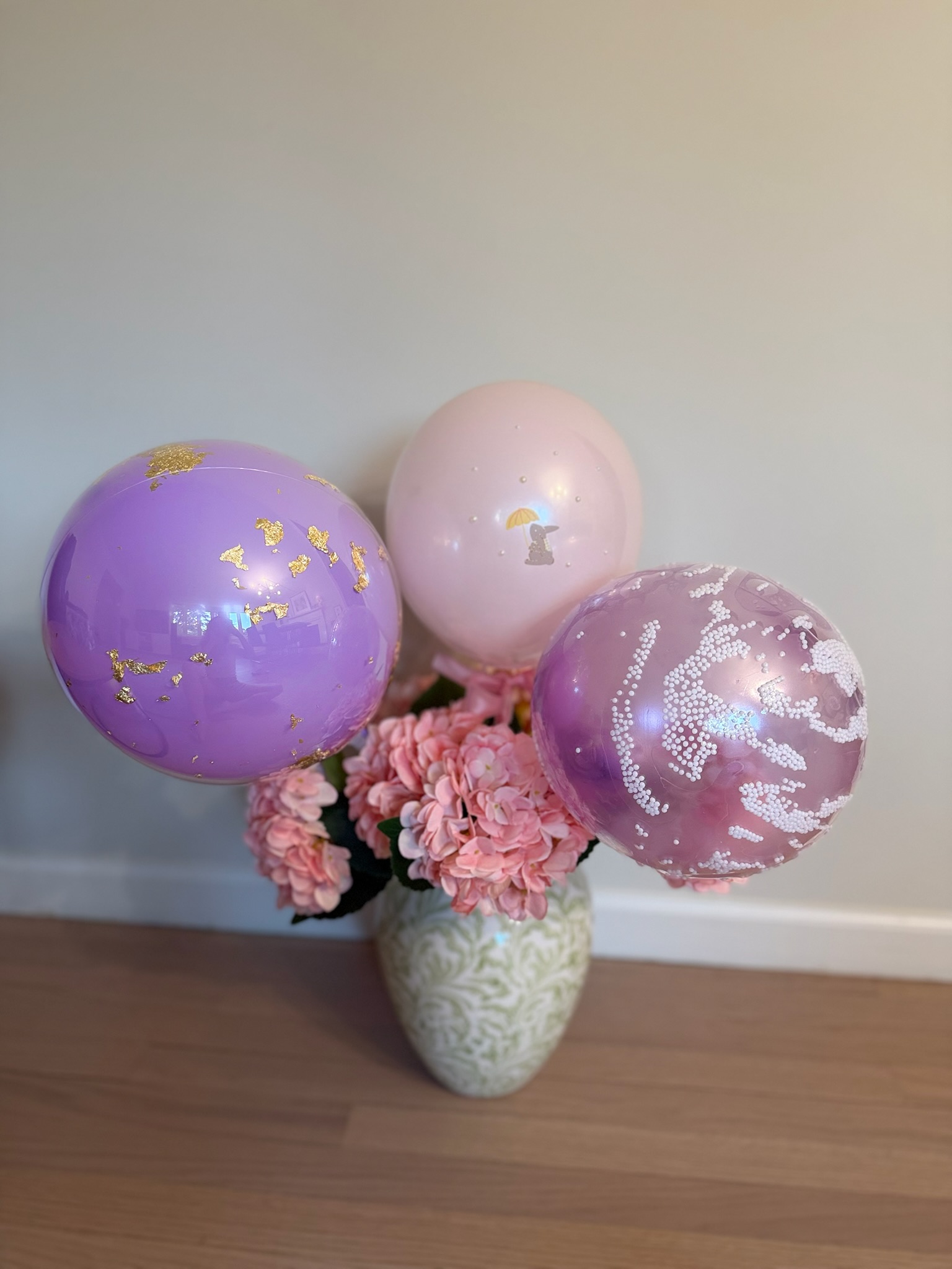 Decorative helium balloon bouquet with gold leaf, bunny print and pearl balloons in floral display