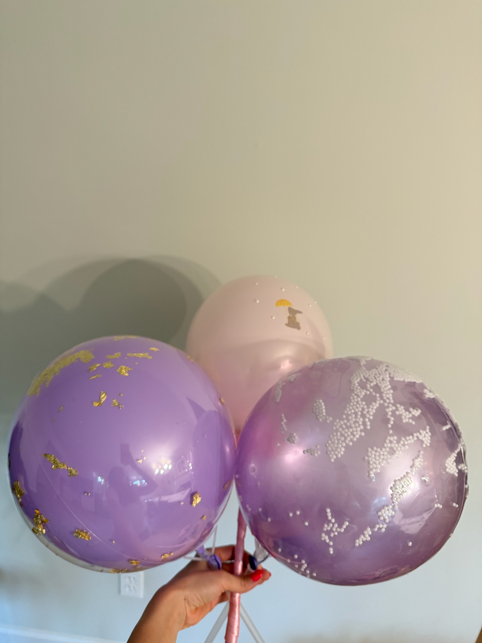 Hand-held helium balloon bouquet in purple, pink and mauve